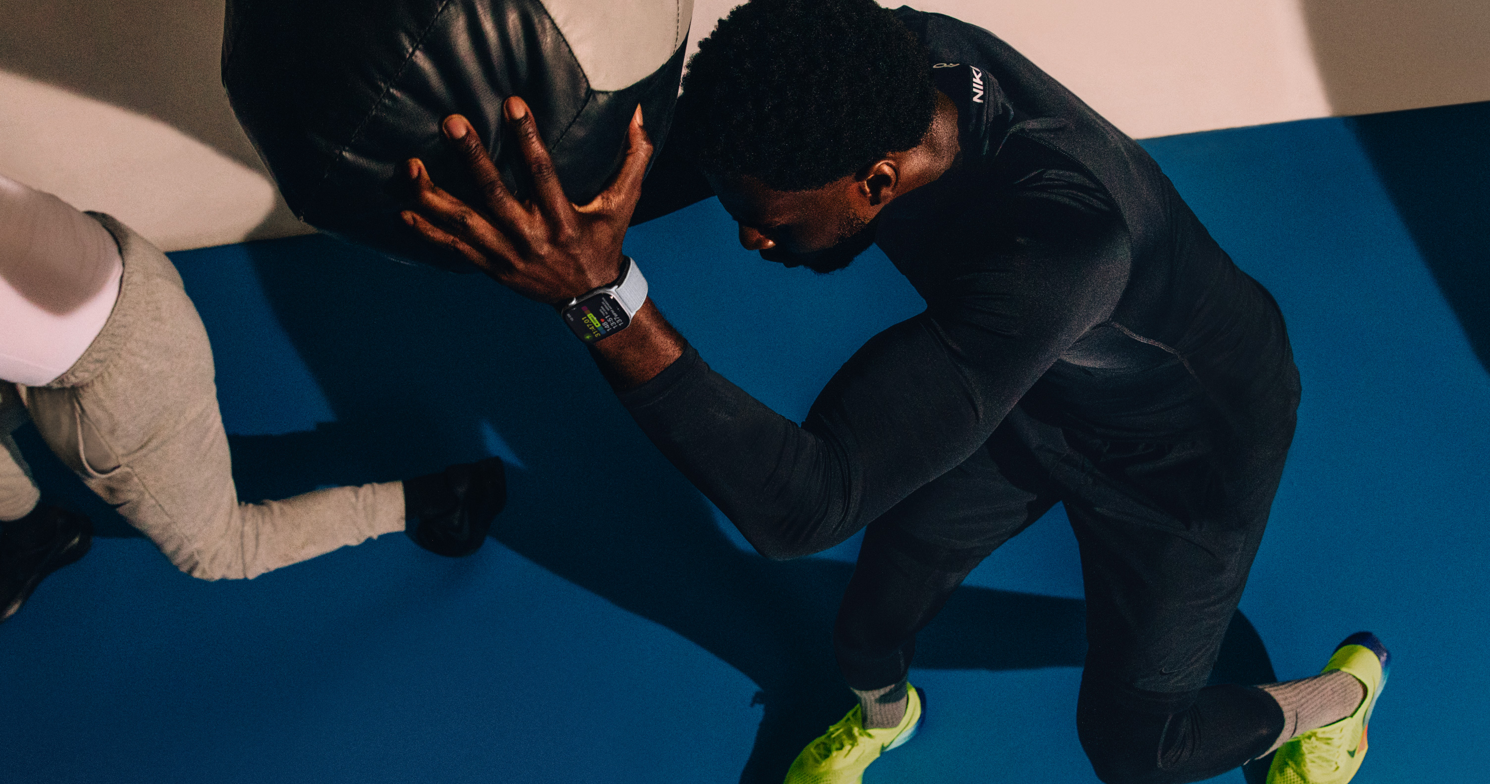 Um homem usando um Apple Watch Series 10 e fazendo exercício com uma bola de peso.