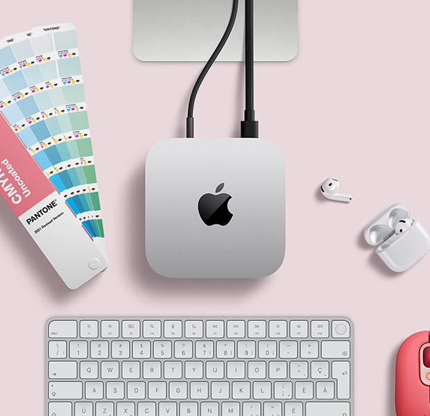 Vue en plongée d’un Mac mini argent sur un bureau, avec des AirPods, un Magic Keyboard blanc et argent et un nuancier de couleurs en éventail