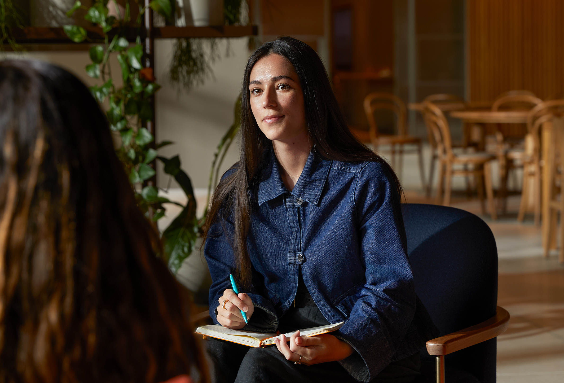 An Apple team member at a table in a common area, speaking with a colleague.