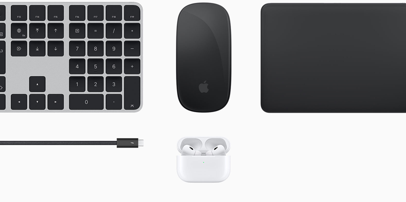 Varios accesorios Mac, como un Magic Keyboard negro con Touch ID, un Magic Mouse negro, un Magic Trackpad negro, un cable negro y unos AirPods blancos dentro de un estuche de carga blanco.