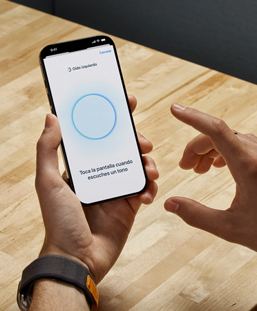 Una persona usando unos AirPods Pro 2 sostiene un iPhone en la mano mientras usa la nueva funcionalidad Prueba de Audición