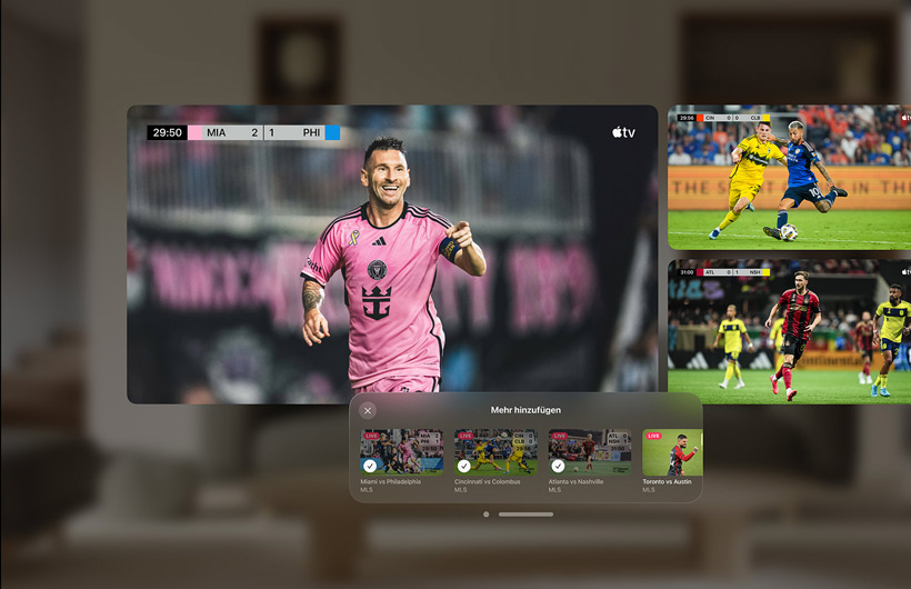 Ein Mann, der eine Apple Vision Pro trägt, sitzt auf einer Couch im Wohnzimmer. Vor ihm ist ein großer Videobildschirm neben zwei kleineren Bildschirmen zu sehen, die jeweils ein anderes Sportereignis zeigen. Unter dem großen Bildschirm befindet sich ein Auswahlfenster mit dem Titel „Mehr hinzufügen“