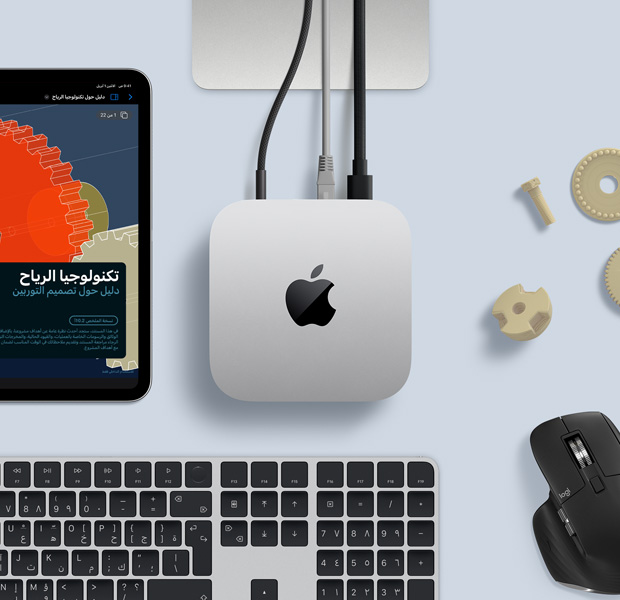 لقطة علوية لجهاز Mac mini فضي اللون ضمن إعداد مكتبي مع لوحة مفاتيح لاسلكية باللونين الأسود والفضي وماوس لاسلكي أسود وجهاز iPad