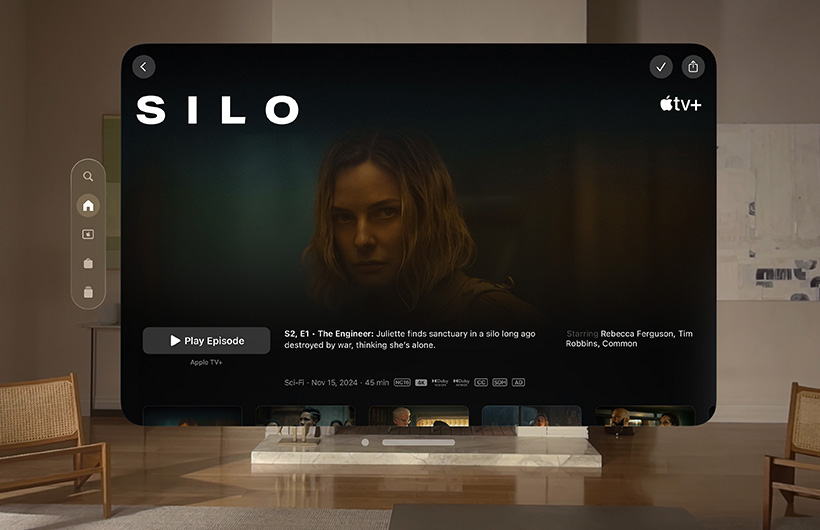 The Apple TV experience of Apple Vision Pro is displayed in a living room. It shows a still image from the Apple TV+ series Silo