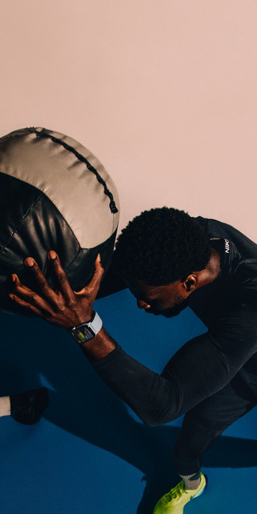 A man wearing an Apple Watch Series 10 holds a medicine ball during a workout.
