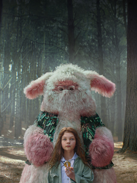 A young girl holding a compass, standing in a forrest with a large, friendly, fictional creature behind her. 