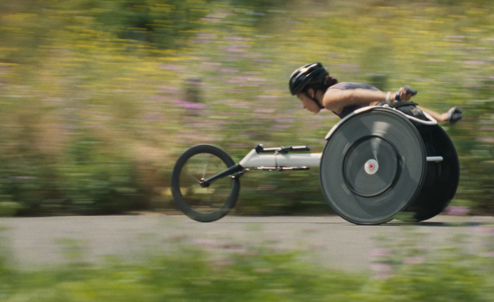 Woman on a racing wheelchair, in motion.