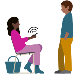 Una persona con un apparecchio acustico mentre cammina con uno zaino da trekking sulle spalle guardando l’iPhone che tiene in mano