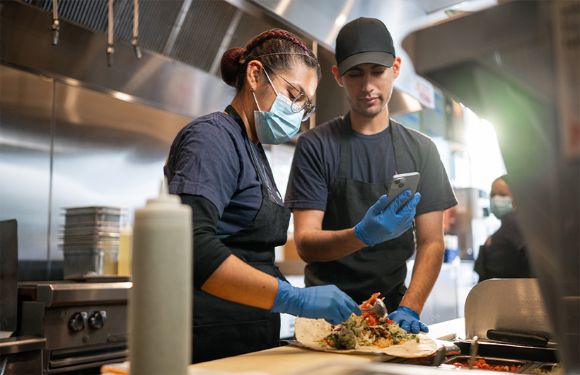 An employee learns how to roll a burrito “the Sisig” way.