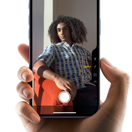 Hand holding an iPhone 16 in Ultramarine, with the thumb sliding along the Camera Control button to adjust the depth of field