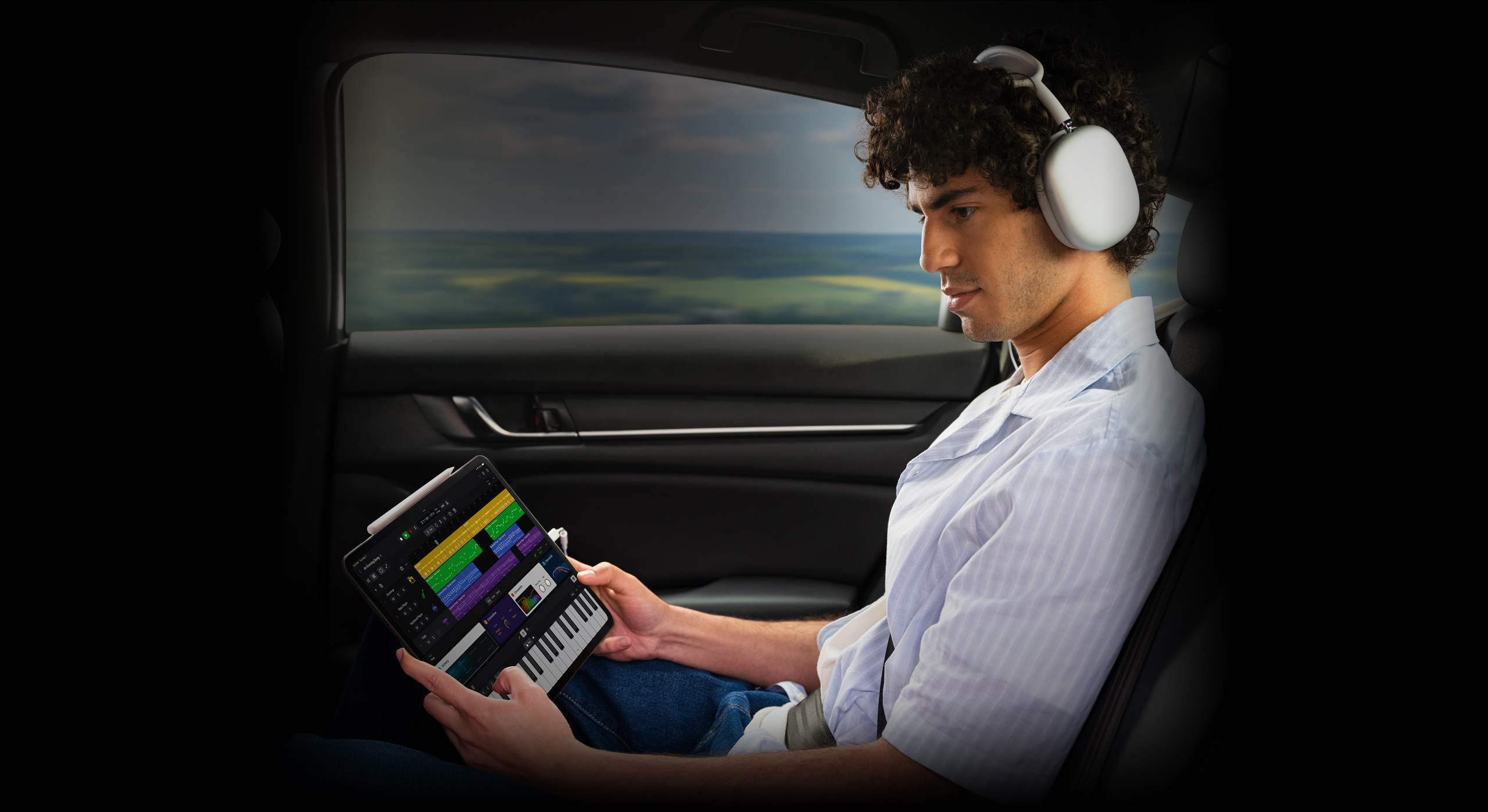 A person wearing headphones touches an iPad Pro screen to create a beat in Logic Pro for iPad.